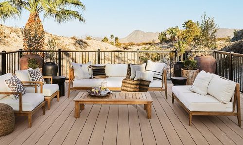 A deck overlooks desert hills and palm trees with a white-cushioned outdoor living furniture set centered to enjoy the view.